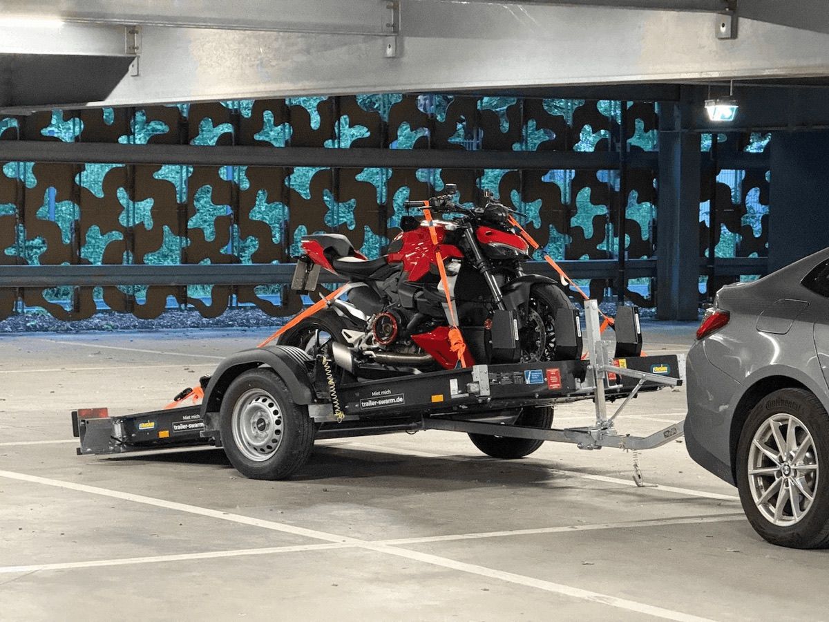 Ducati Streetfighter V2 mit orangen Spanngurten auf dem noch abgesenkten Unsinn-Anhänger von Trailer Swarm festgezurrt, an ein Auto gekuppelt in einer Tiefgarage